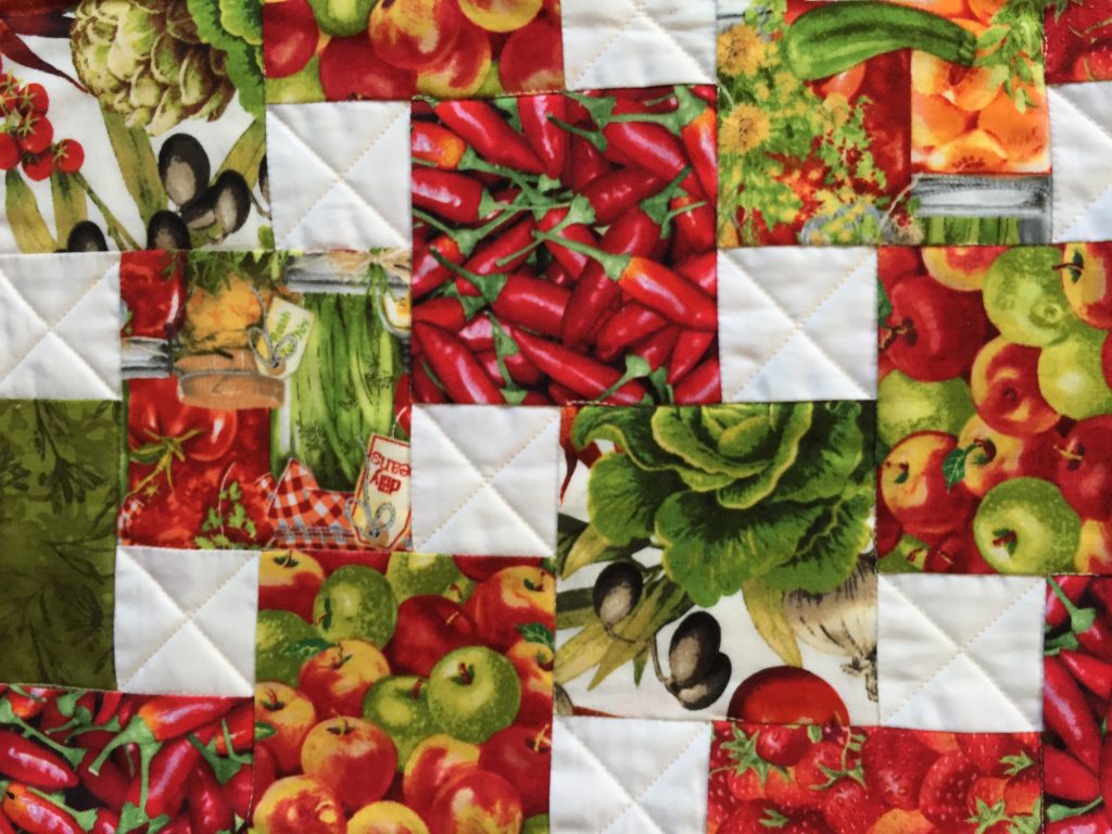 Step-down piecing produce quilt in reds and greens