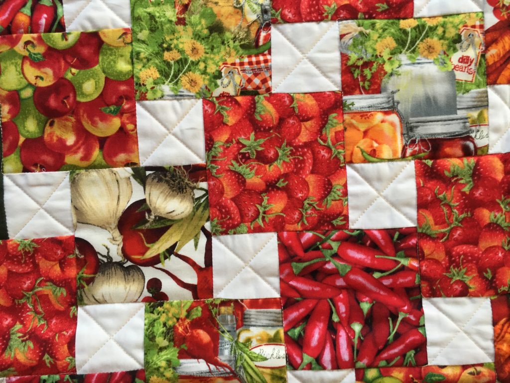 Step-down piecing produce quilt in reds and greens